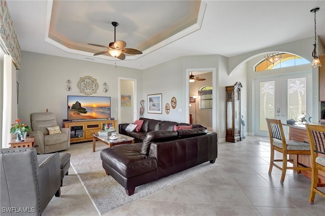 living room featuring a tray ceiling, ceiling fan, and french doors