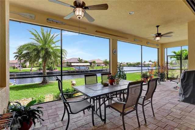 sunroom with a water view and ceiling fan