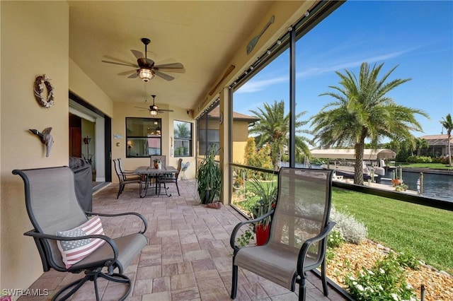 sunroom / solarium with ceiling fan and a water view