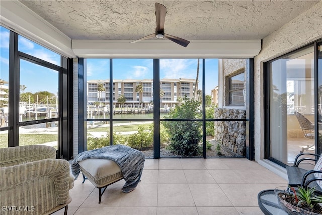 sunroom with ceiling fan and a water view