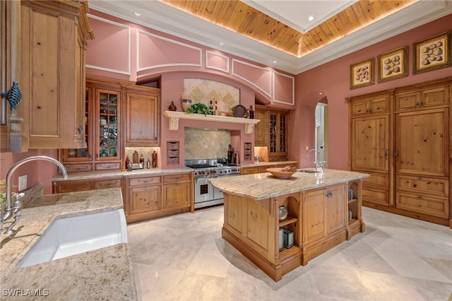 kitchen featuring sink, light stone counters, wooden ceiling, a kitchen island with sink, and range with two ovens