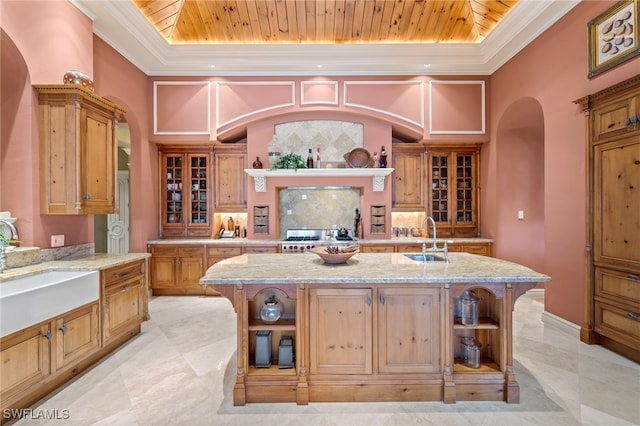 kitchen featuring a raised ceiling, a center island with sink, and wood ceiling