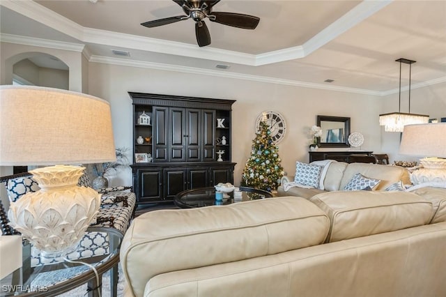 living room featuring ceiling fan, ornamental molding, and a tray ceiling