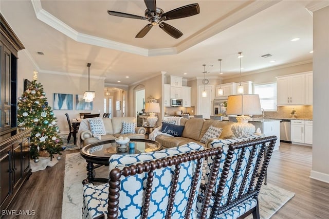 living room featuring ornamental molding, dark hardwood / wood-style floors, ceiling fan, and a tray ceiling