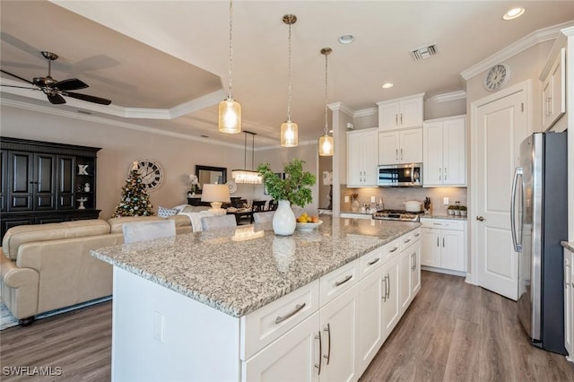 kitchen featuring hanging light fixtures, white cabinetry, appliances with stainless steel finishes, and a center island