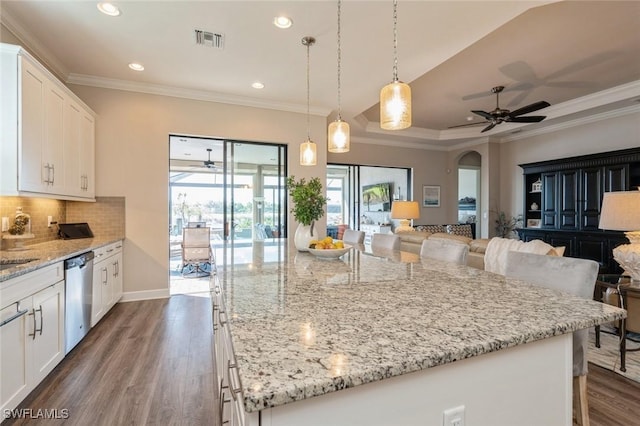 kitchen featuring a kitchen island, tasteful backsplash, white cabinetry, a kitchen bar, and stainless steel dishwasher