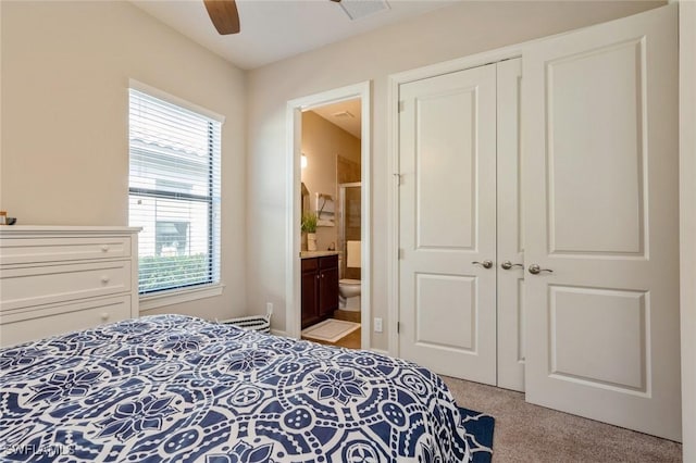 carpeted bedroom featuring multiple windows, ceiling fan, ensuite bathroom, and a closet