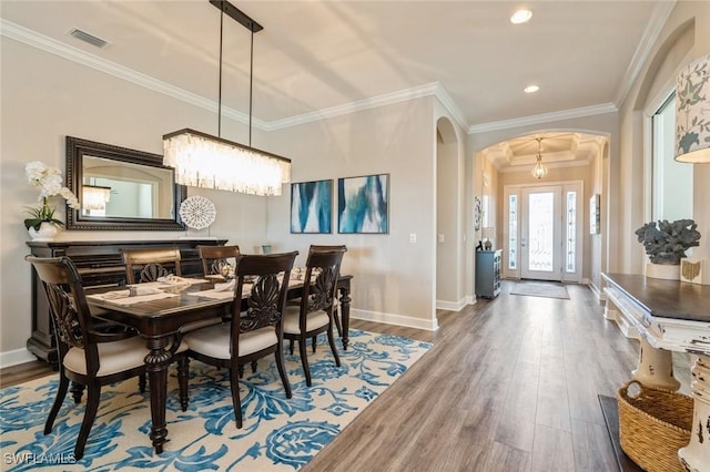 dining area with ornamental molding, a chandelier, and hardwood / wood-style floors