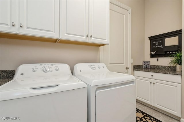 laundry room with light tile patterned floors, cabinets, and washing machine and clothes dryer