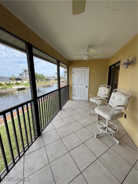 unfurnished sunroom with a wealth of natural light, ceiling fan, and a water view