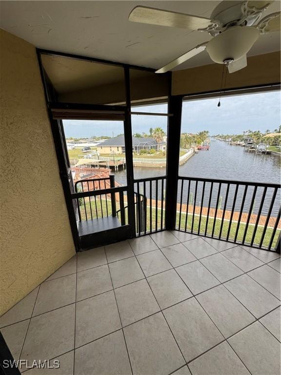 unfurnished sunroom featuring a water view and ceiling fan