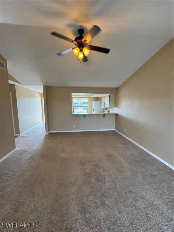 carpeted spare room featuring vaulted ceiling and ceiling fan