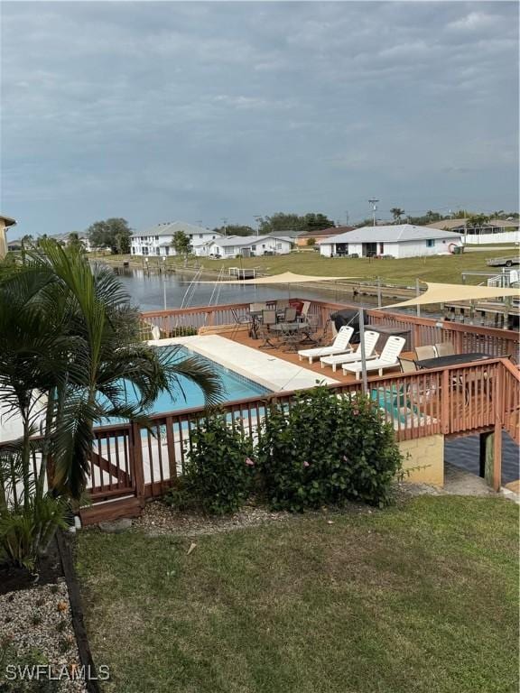 view of swimming pool with a deck with water view and a yard