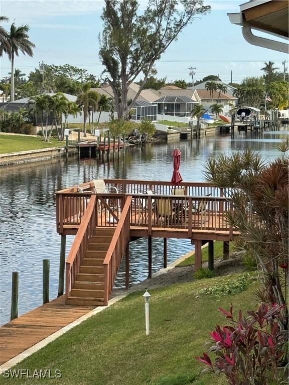 view of dock with a yard and a water view