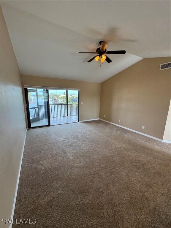 carpeted empty room featuring vaulted ceiling and ceiling fan