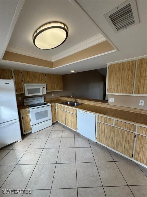 kitchen featuring ornamental molding, white appliances, a tray ceiling, sink, and light tile patterned floors