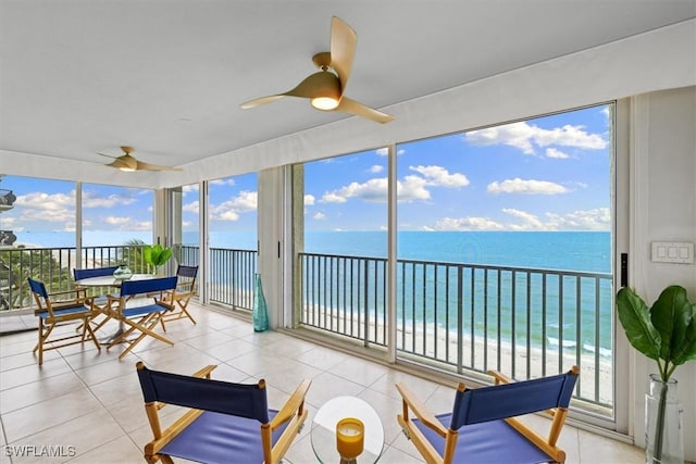 sunroom featuring a water view, ceiling fan, and a view of the beach