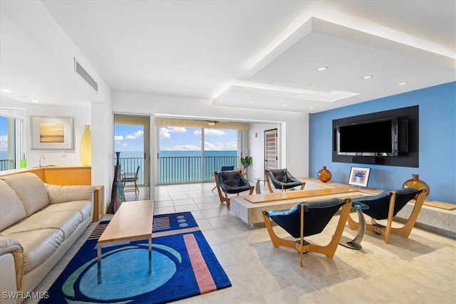 living room featuring a tray ceiling and light tile patterned floors