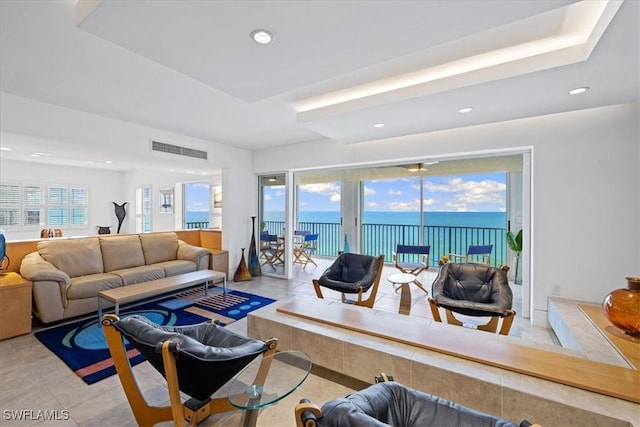 living room with a water view, a wealth of natural light, and light tile patterned floors