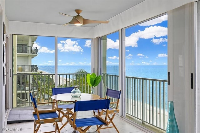 sunroom / solarium featuring a water view, plenty of natural light, and ceiling fan