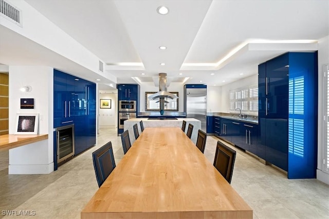 dining space with a raised ceiling, light tile patterned flooring, sink, and wine cooler