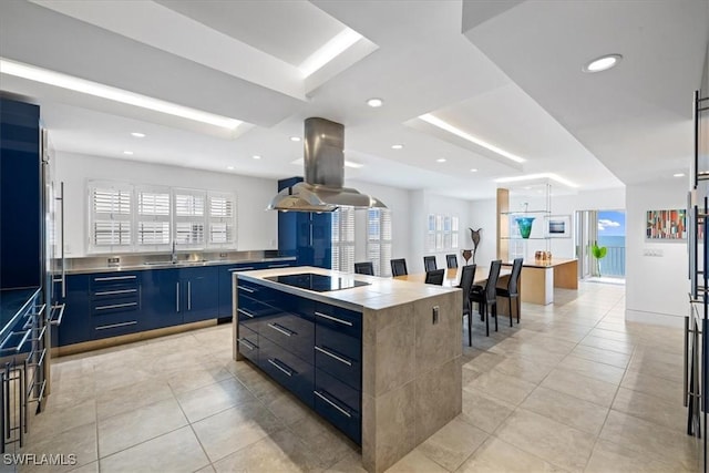 kitchen featuring a kitchen island, island range hood, blue cabinets, sink, and black electric stovetop