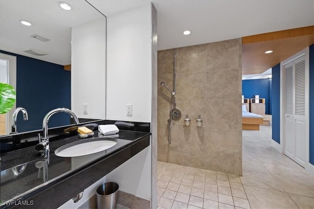 bathroom with vanity, a tile shower, and tile patterned floors