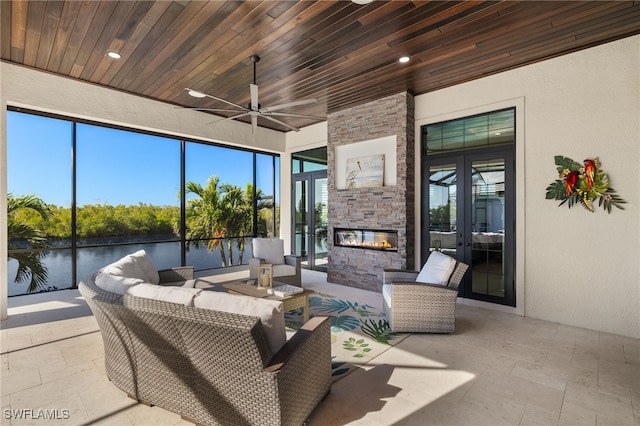 sunroom with french doors, an outdoor stone fireplace, wooden ceiling, and a water view