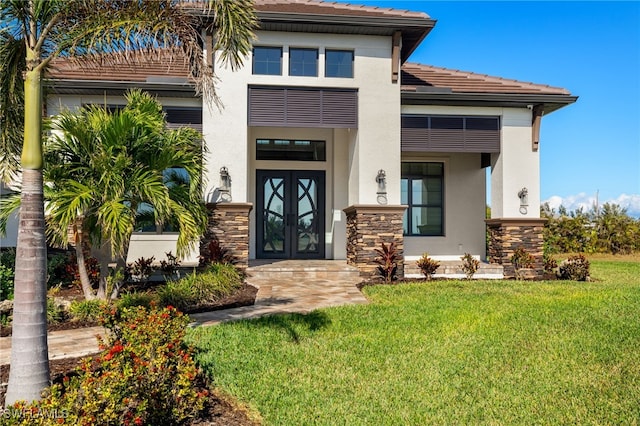 view of exterior entry with a lawn and french doors