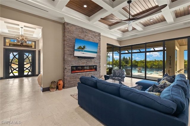 living room featuring a stone fireplace, coffered ceiling, crown molding, beam ceiling, and ceiling fan with notable chandelier