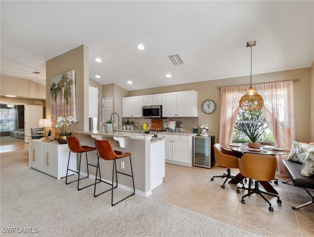 kitchen featuring wine cooler, tasteful backsplash, white cabinetry, hanging light fixtures, and light tile patterned floors