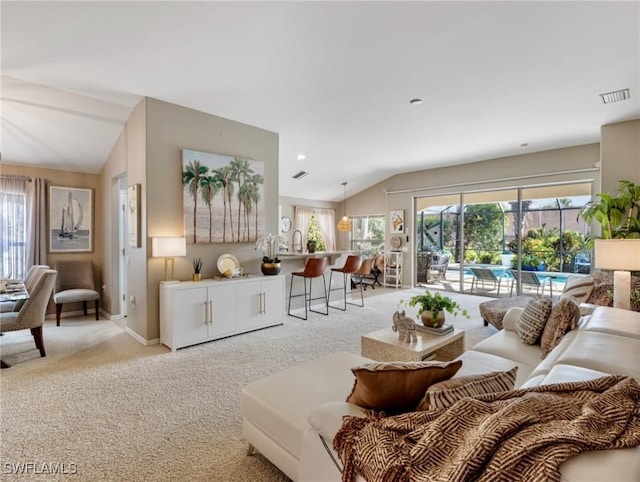 living room featuring vaulted ceiling, a healthy amount of sunlight, and light colored carpet