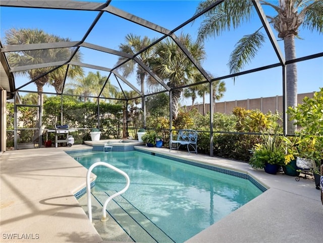 view of pool featuring a patio, glass enclosure, and an in ground hot tub