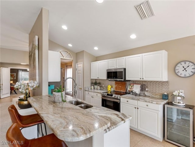 kitchen featuring sink, white cabinets, beverage cooler, and stainless steel appliances