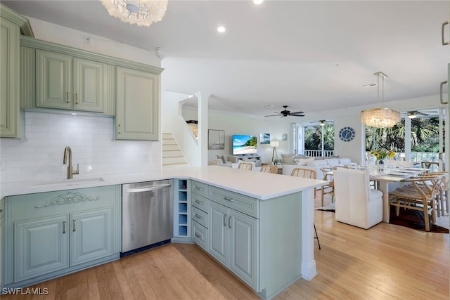 kitchen featuring dishwasher, kitchen peninsula, sink, and decorative light fixtures