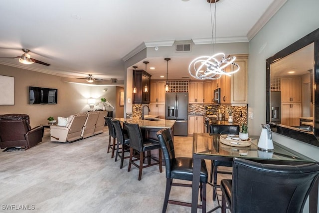 dining area featuring crown molding, sink, and ceiling fan with notable chandelier