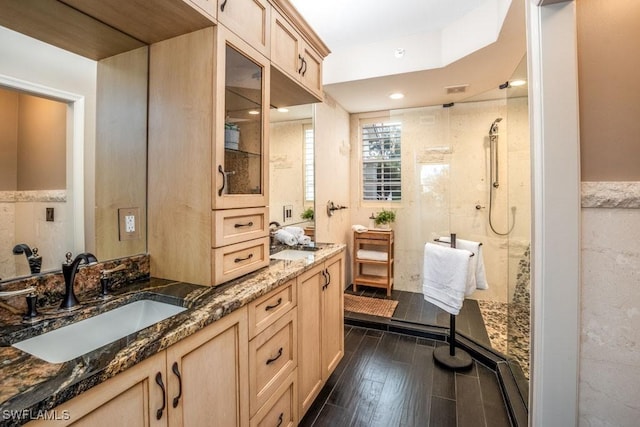 bathroom with a tile shower, vanity, and tile walls