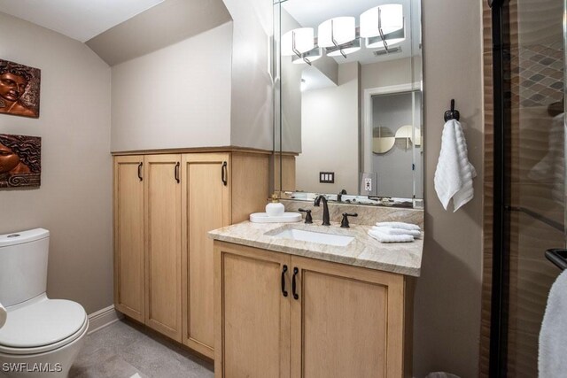 bathroom with tile patterned flooring, vanity, toilet, and vaulted ceiling