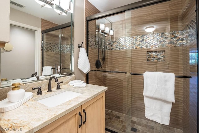 bathroom featuring a shower with door and vanity