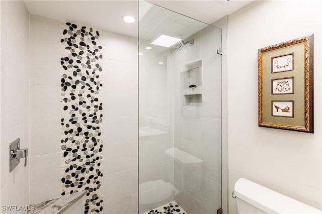 bathroom with a tile shower and toilet