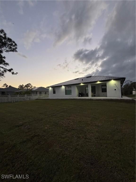 back house at dusk with a lawn