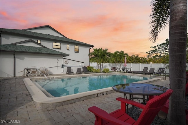 pool at dusk with a patio area