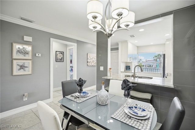 tiled dining room featuring an inviting chandelier, ornamental molding, and sink