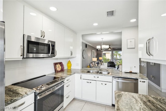 kitchen with sink, stainless steel appliances, an inviting chandelier, kitchen peninsula, and white cabinets