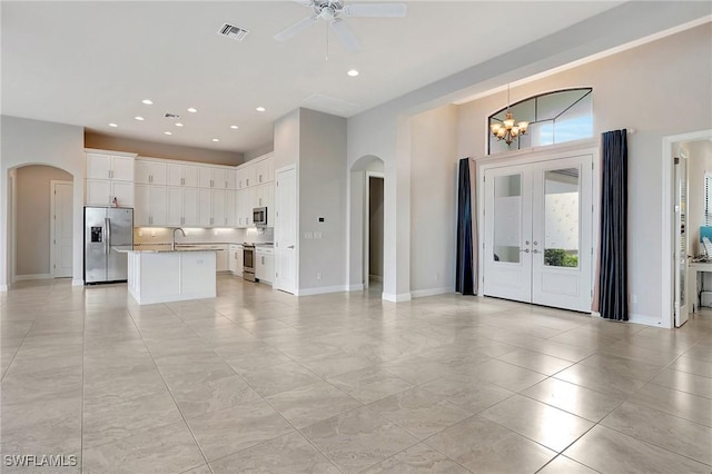 kitchen featuring white cabinetry, french doors, sink, a kitchen island with sink, and appliances with stainless steel finishes