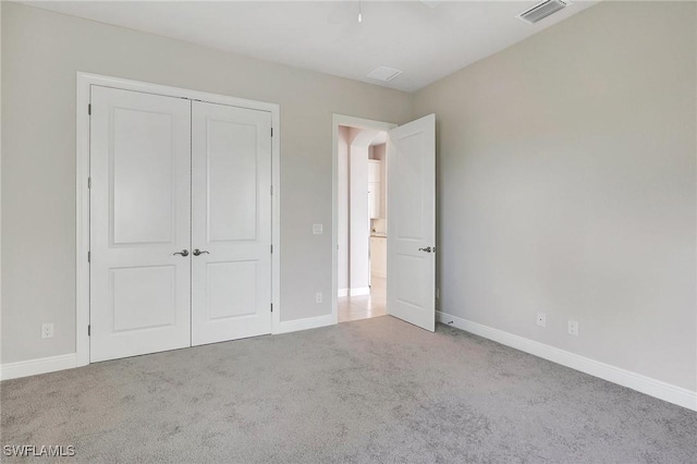 unfurnished bedroom with light colored carpet and a closet