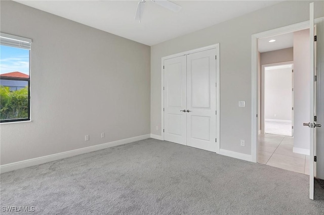 unfurnished bedroom featuring ceiling fan, light carpet, and a closet