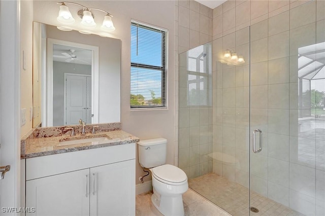 bathroom with vanity, a shower with door, ceiling fan, tile patterned flooring, and toilet