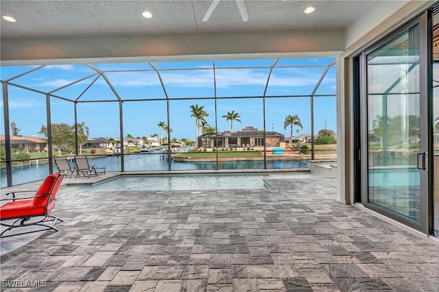 view of swimming pool with a lanai, a patio area, ceiling fan, and a water view