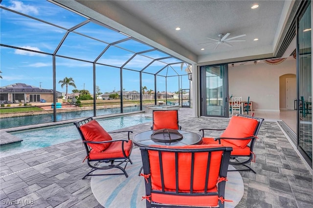 view of patio / terrace with glass enclosure, ceiling fan, and an outdoor fire pit